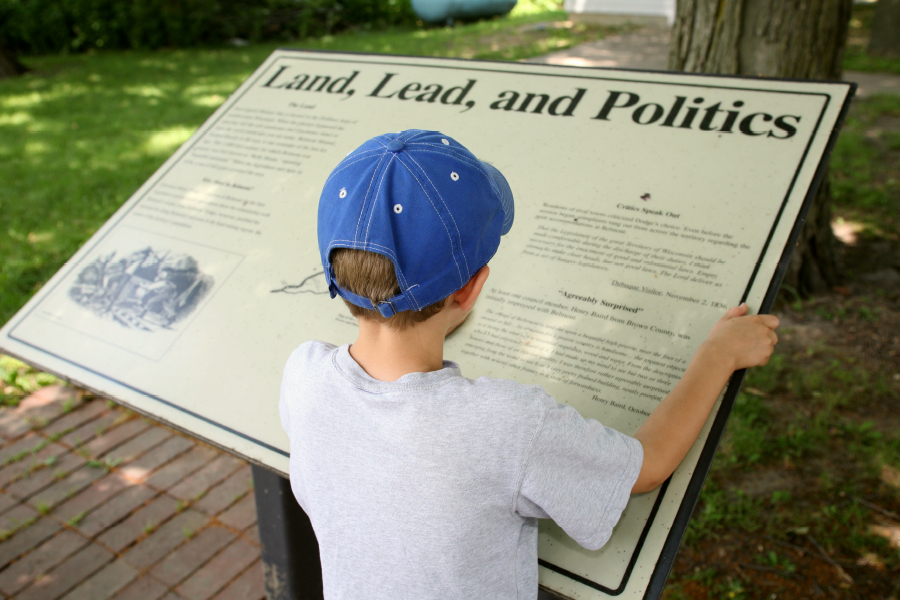 Child reads the Land, Lead, and Politics exhibit board